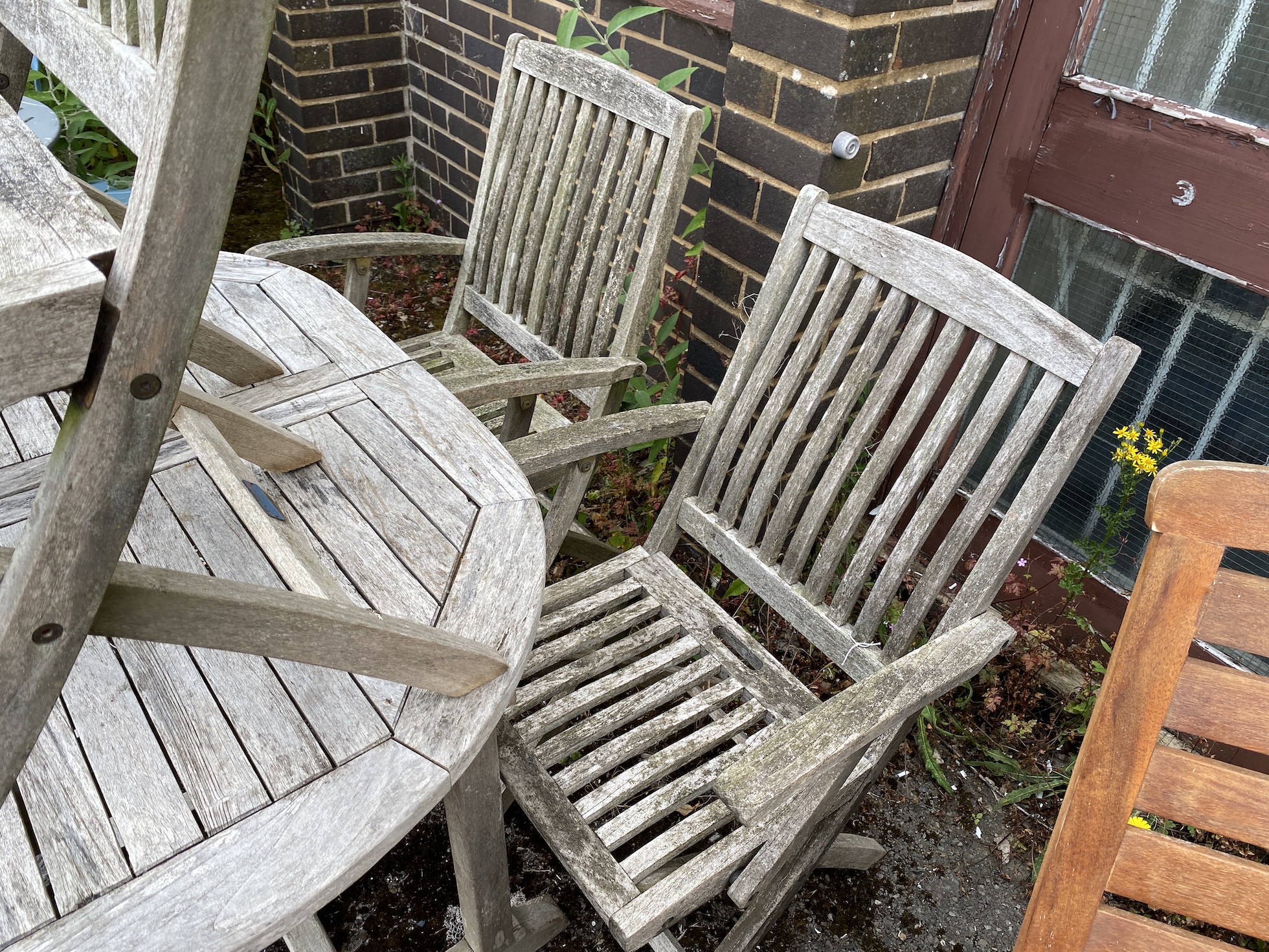 A weathered teak garden table, length 121cm, depth 89cm, height 75cm, and four folding elbow chairs